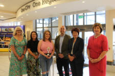 Group of six people with female in centre holding an award
