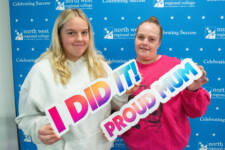 two women smiling - they are standing in front of signs with NWRC on them