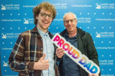 Two males with a proud dad sign