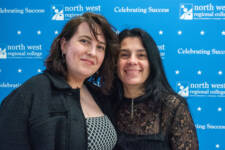 two women smiling - they are standing in front of signs with NWRC on them