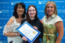 Three women smiling - they are standing in front of signs with NWRC on them