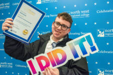 A male student holds a sign that spells out I did it