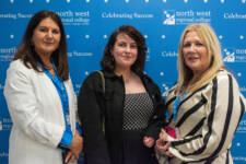Three women smiling - they are standing in front of signs with NWRC on them
