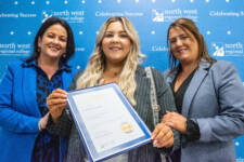 Three women smiling - they are standing in front of signs with NWRC on them