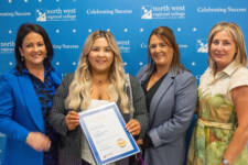 Four women smiling - they are standing in front of signs with NWRC on them