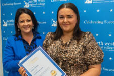 two women smiling - they are standing in front of signs with NWRC on them