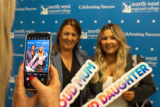 two women smiling - they are standing in front of signs with NWRC on them