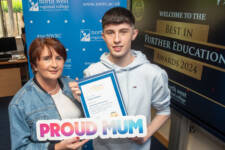 A mum and son two hold a certificate and a proud mum sign
