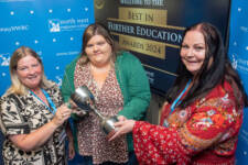 Three woman smile, they are holding a trophy