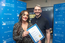 man and women smile for the camera - the woman is holding a certficate