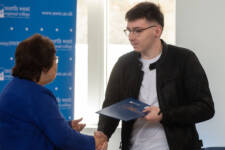 Student receives certificate from a woman shaking his hand