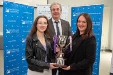Two women and a man with a trophy.