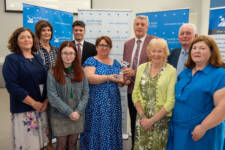 Group picture of people, the lady in the middle is being presented with an award