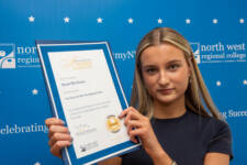 student holds a certificate with branding behind them