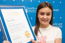 student holds a certificate with branding behind them