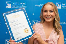 student holds a certificate with branding behind them