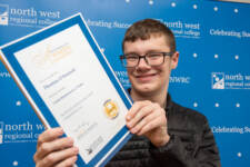 student holds a certificate with branding behind them