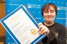 student holds a certificate with branding behind them