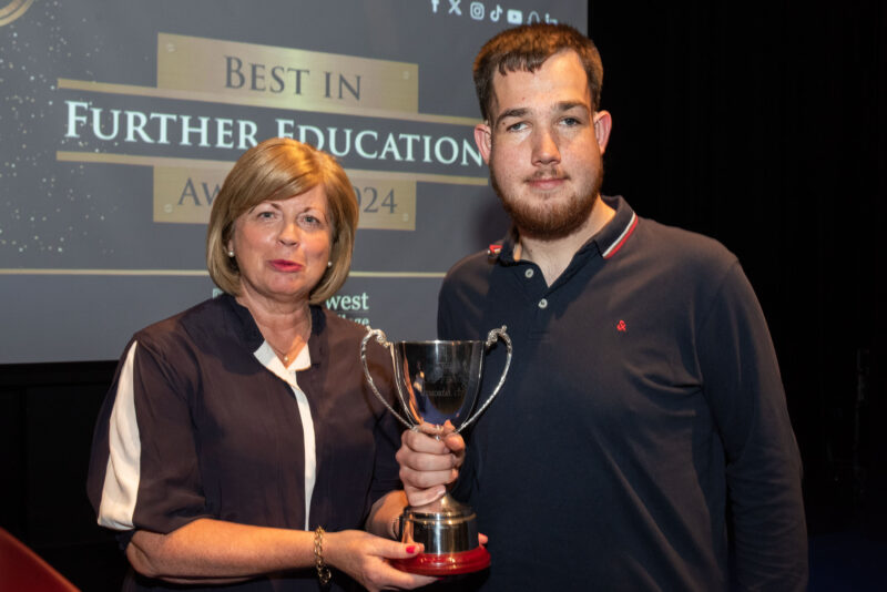Woman and man on a stage holding a trophy. The screen behind says Best in Further Education awards 2024