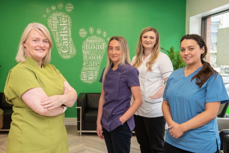 Four female podiatrists in a foot surgery. They are wearing scrubs.