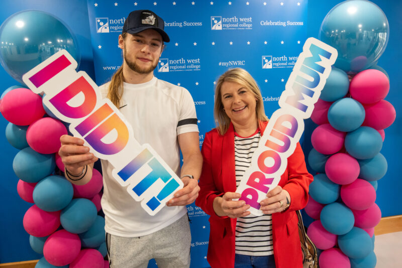 Mum and son stand in front of NWRC branding with a sign that says proud mum.
