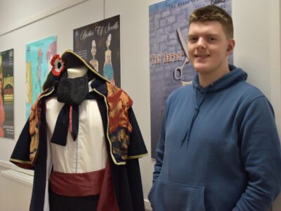 Male student beside a mannequin with a costume on it