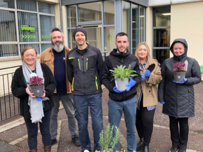 students and staff pictured holding plants