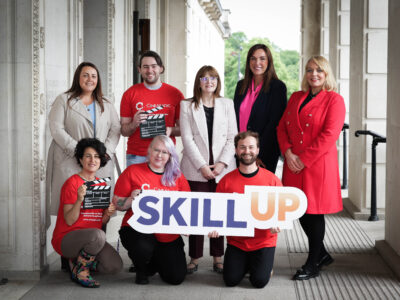 Group of people in an official building holding a graphic that says Skill Up