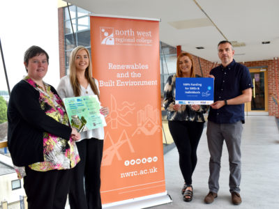 Four people standing beside signage for environmental sustainability