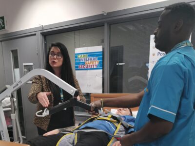 women in a teaching environment explaining nursing techniques to a student n a blue uniform