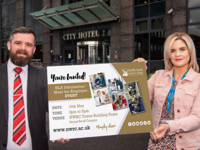 Man and woman pictured outside hotel holding a sign advertising the HLA event at NWRC on May 10.