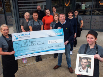 NWRC staff handing large cheque to Foyle Hospice, one staff member is holding a picture of Colman O'Driscoll