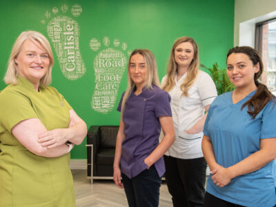 Four female podiatrists in a foot surgery. They are wearing scrubs.