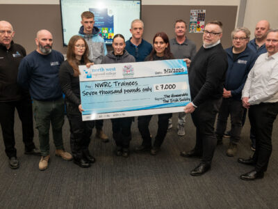 group of ten people in a classroom holding a cheque made out to trainees for £1,000