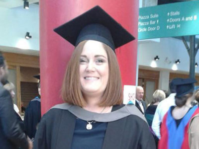 NWRC student smiling at graduation ceremony wearing graduation robes and mortarboard