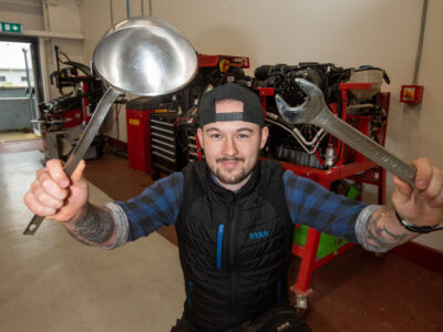 man in garage holding a ladle and spanner