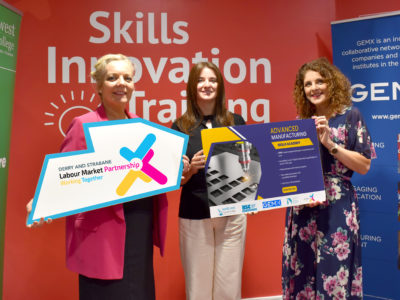 Three women holding up signs about the Advanced Manufacturing Academy