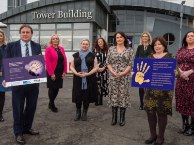Group of people pictured outside NWRC holding a board raising awareness of the 16 days of action.