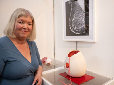 Women stands in front of an art display during an exhibition. There is a picture of mammogram.