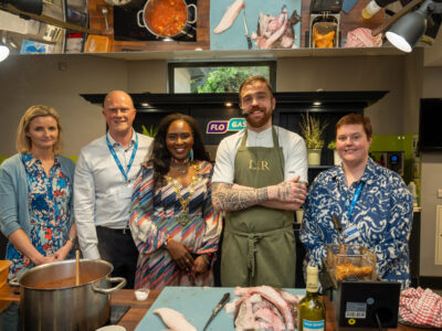 group of five stand in a demo kitchen with raw fish on the boards in front of them.