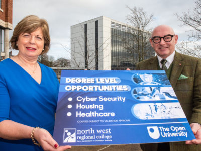 Two individuals pictured outside the college holding a photo prop highlighting the new courses offered at NWRC with the OU