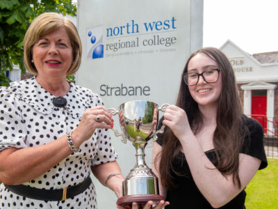 Two people pictured outside the campus with a trophy