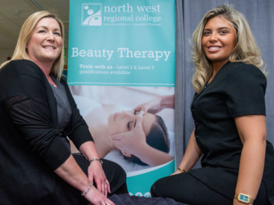 Female lecturer and students in front of a pop up banner for beauty