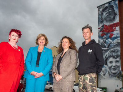 Three women and a man pictured at the Amelia Earhart mural