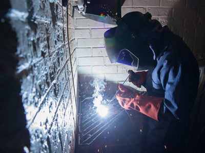 Welder in protective clothing, welding in workshop