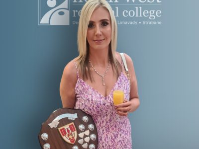 woman in a pink dress holding a shield. The background is NWRC signage