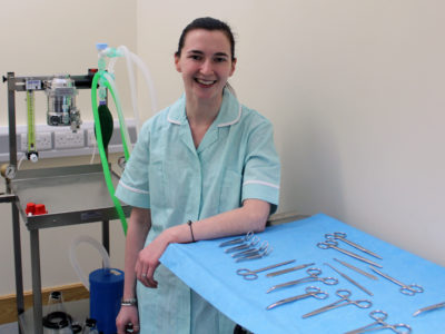 Student Emily pictured in Veterinary Surgery with tools such as scissors on a table in front of her.