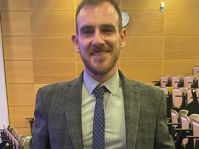 Man pictured in a lecture theatre smiling
